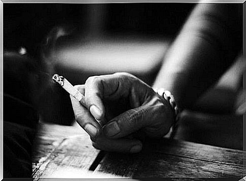 Hand with cigarette.  Don't forget that smoking can lead to mouth cancer.