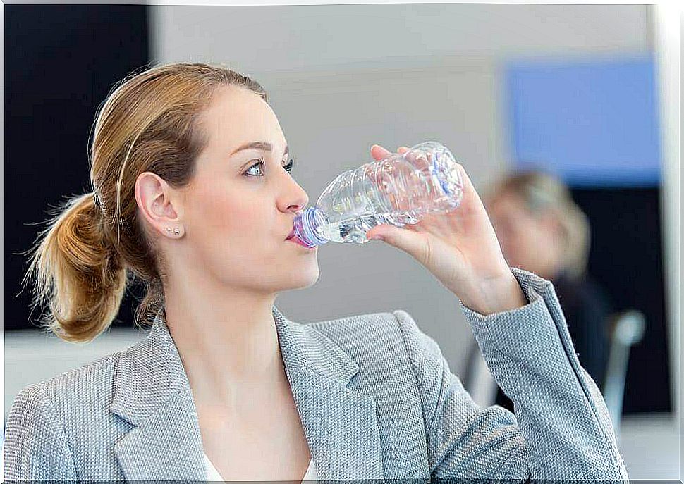 A woman drinks water from a plastic bottle.